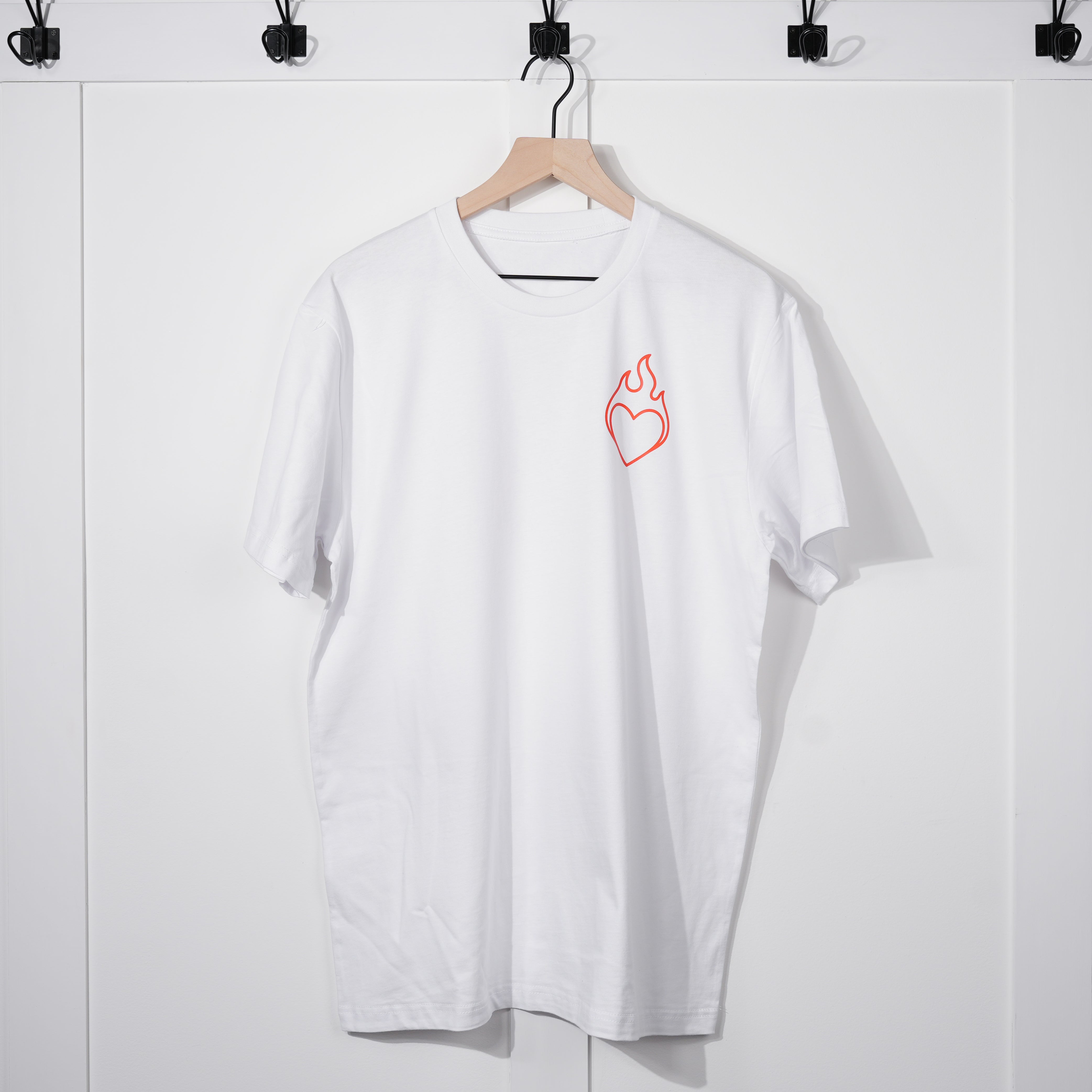 White t-shirt with a red heart and flame design on a hanger against a white background